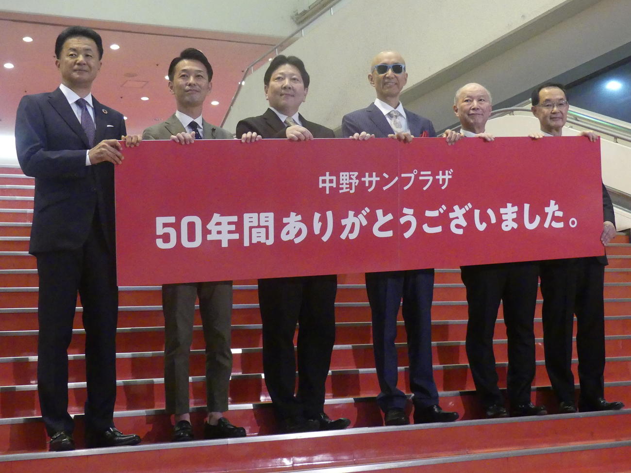 中野サンプラザ閉館に伴い、サンプラザ中野くん（右から3人目）ら関係者が「中野サンプラザ　50年間ありがとうございました」のボードを掲げた＝2023年7月2日
