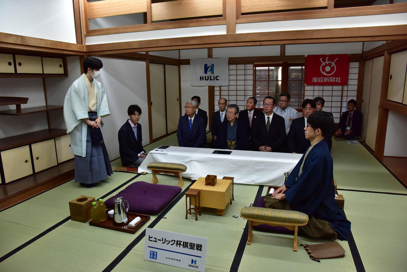 藤井聡太棋聖（左）は午前8時49分に入室して関係者にあいさつする（右は午前8時44分に入室していた佐々木大地七段）（日本将棋連盟提供）