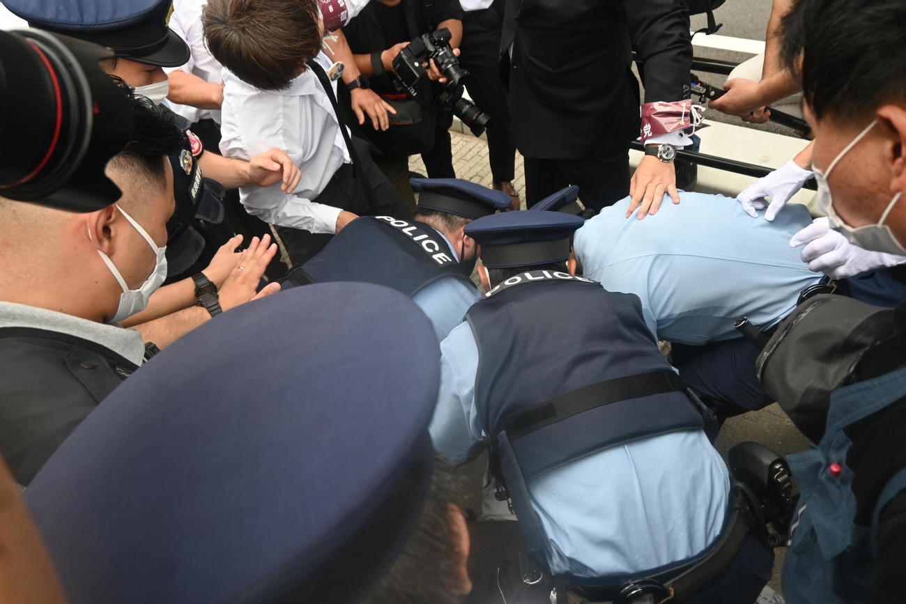 献花台の近くでアルミホイールの棒を持っていた男性は激しく抵抗し、警察官に取り押さえられる（撮影・松浦隆司）