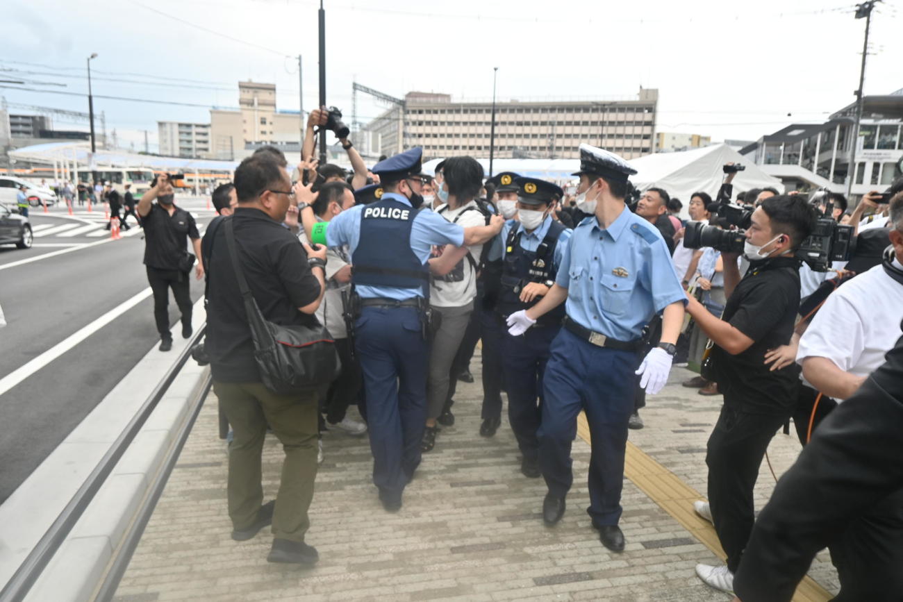 献花台の近くでアルミホイールの棒を持っていた男性は激しく抵抗し、警察官に取り押さえられ、“連行”される（撮影・松浦隆司）