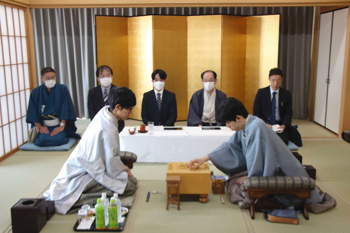2日目の再開を前に駒を並べる先手の藤井聡太王位（右）と後手佐々木大地七段（左、日本将棋連盟提供）