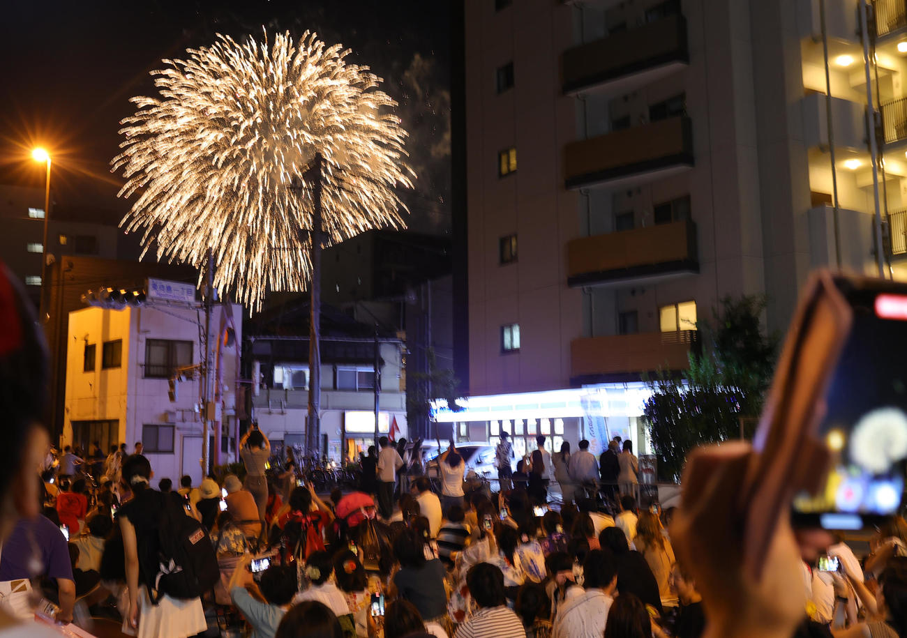 4年ぶりに開催された隅田川花火大会で、建物の間からのぞく花火を見上げる人たち（撮影・野上伸悟）