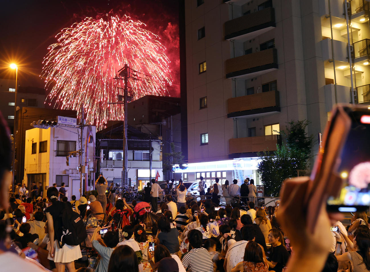 4年ぶりに開催された隅田川花火大会で、建物の間からのぞく花火を見上げる人たち（撮影・野上伸悟）