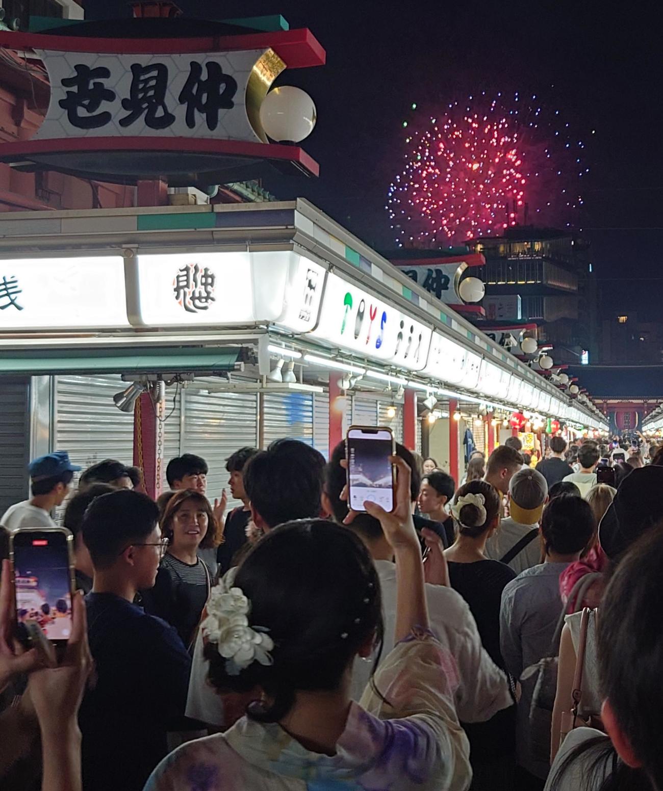 打ち上げ場所からちょっと離れた仲見世通りからも花火が見えた。浴衣姿の女性も思わずスマホでパシャリ（撮影・寺沢卓）