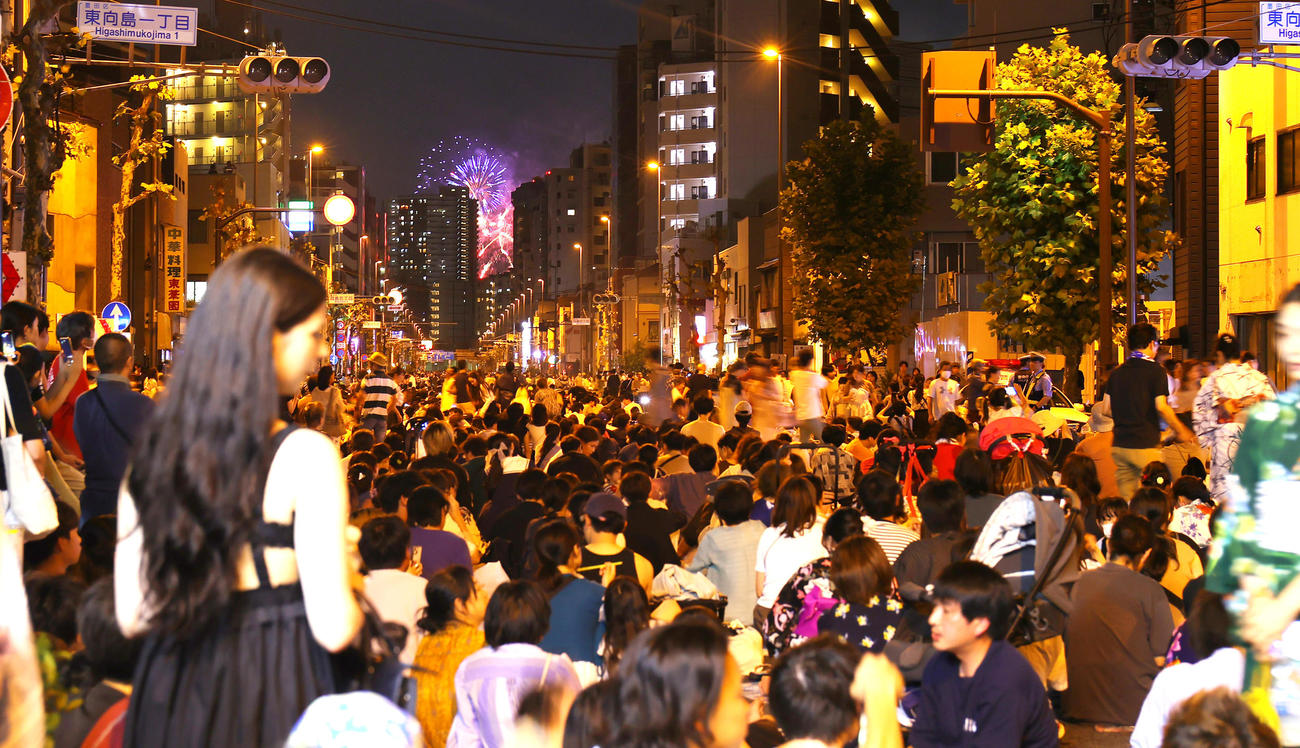 4年ぶりに開催された隅田川花火大会で、建物の間からのぞく花火を見上げる人たち（撮影・野上伸悟）