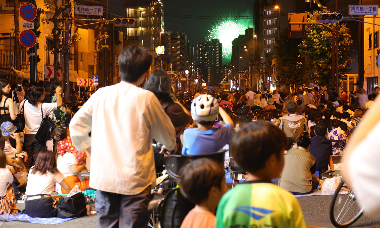 4年ぶりに開催された隅田川花火大会で、建物の間からのぞく花火を見上げる人たち（撮影・野上伸悟）