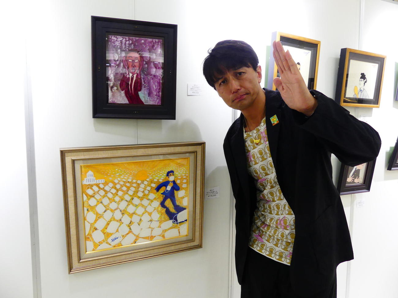 開催中の個展に出展した「文句の叫び」「マスクをまく人」の前でポーズを取る「ザ・ニュースペーパー」の福本ヒデ（撮影・中山知子）
