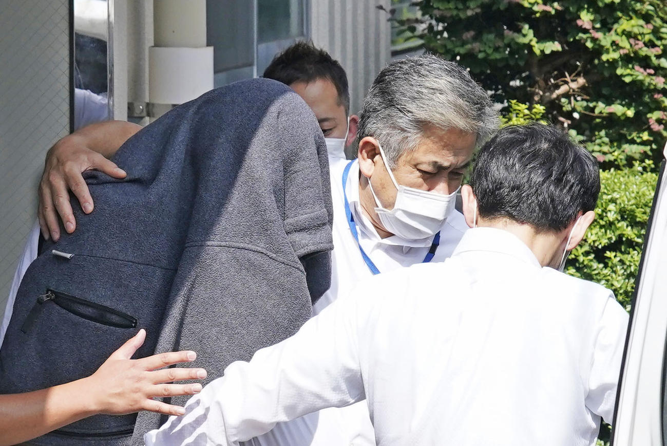 大麻取締法違反などの疑いで逮捕され、寮を出る日本大アメリカンフットボール部員の北畠成文容疑者（左）＝5日午前9時7分、東京都中野区