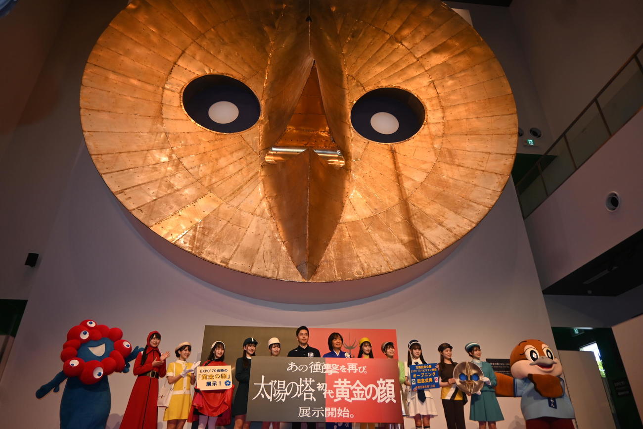 「太陽の塔」の初代「黄金の顔」の前に並ぶ吉村洋文大阪府知事（中央）ら（撮影・松浦隆司）