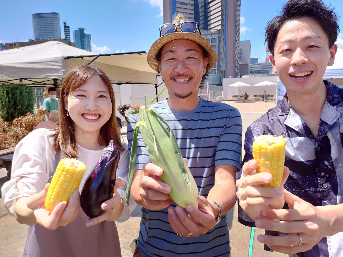 バーベキュー場で出会ったカップルと石川直宏さん（中）は仲良くトウモロコシを持って笑顔（撮影・寺沢卓）
