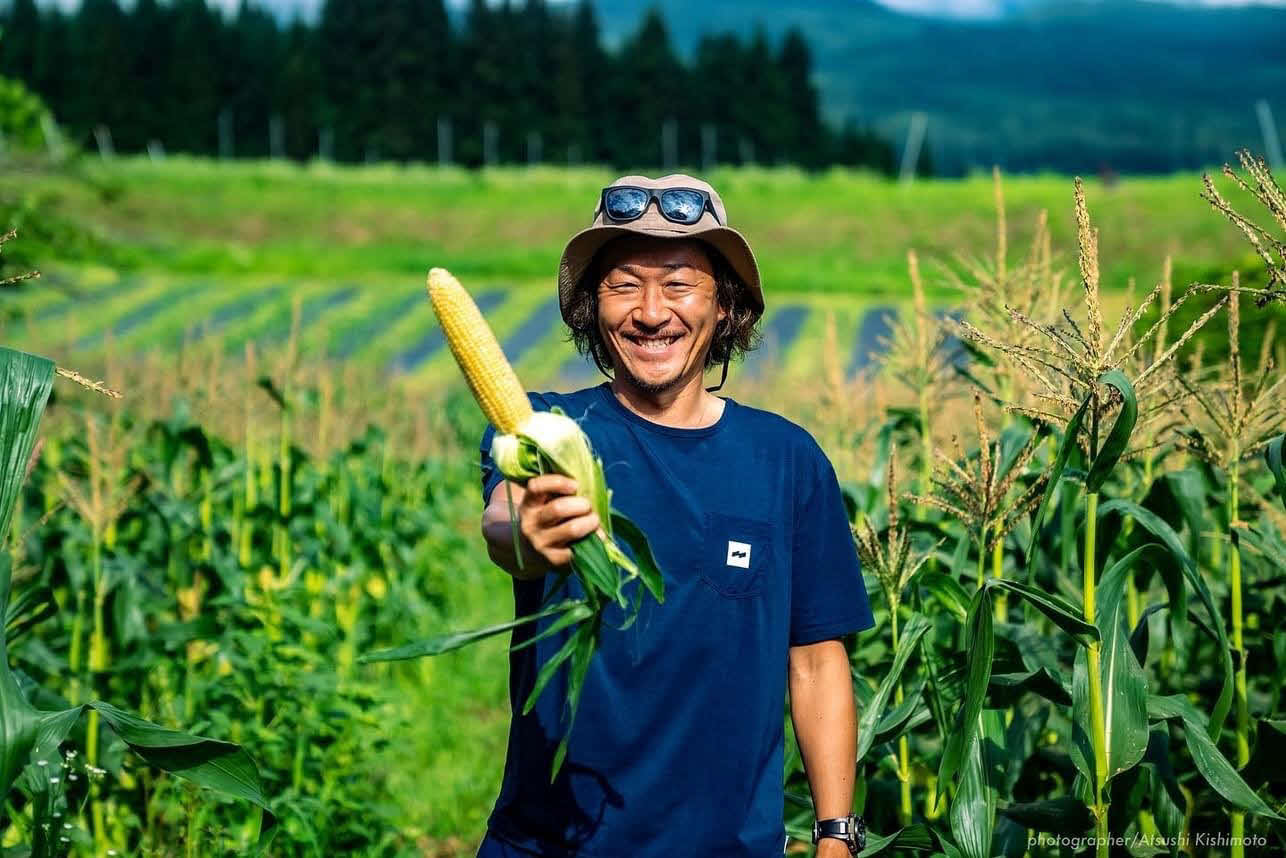 自作のトウモロコシ「なおもろこしゴールド」を手に笑顔を見せる石川直宏さん（撮影・Atsushi Kishimoto）