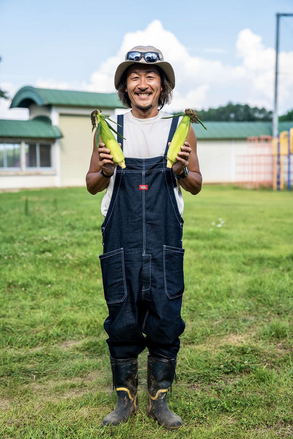 自作のトウモロコシ「なおもろこしゴールド」を持って笑顔の石川直宏さん（撮影・Atsushi Kishimoto）