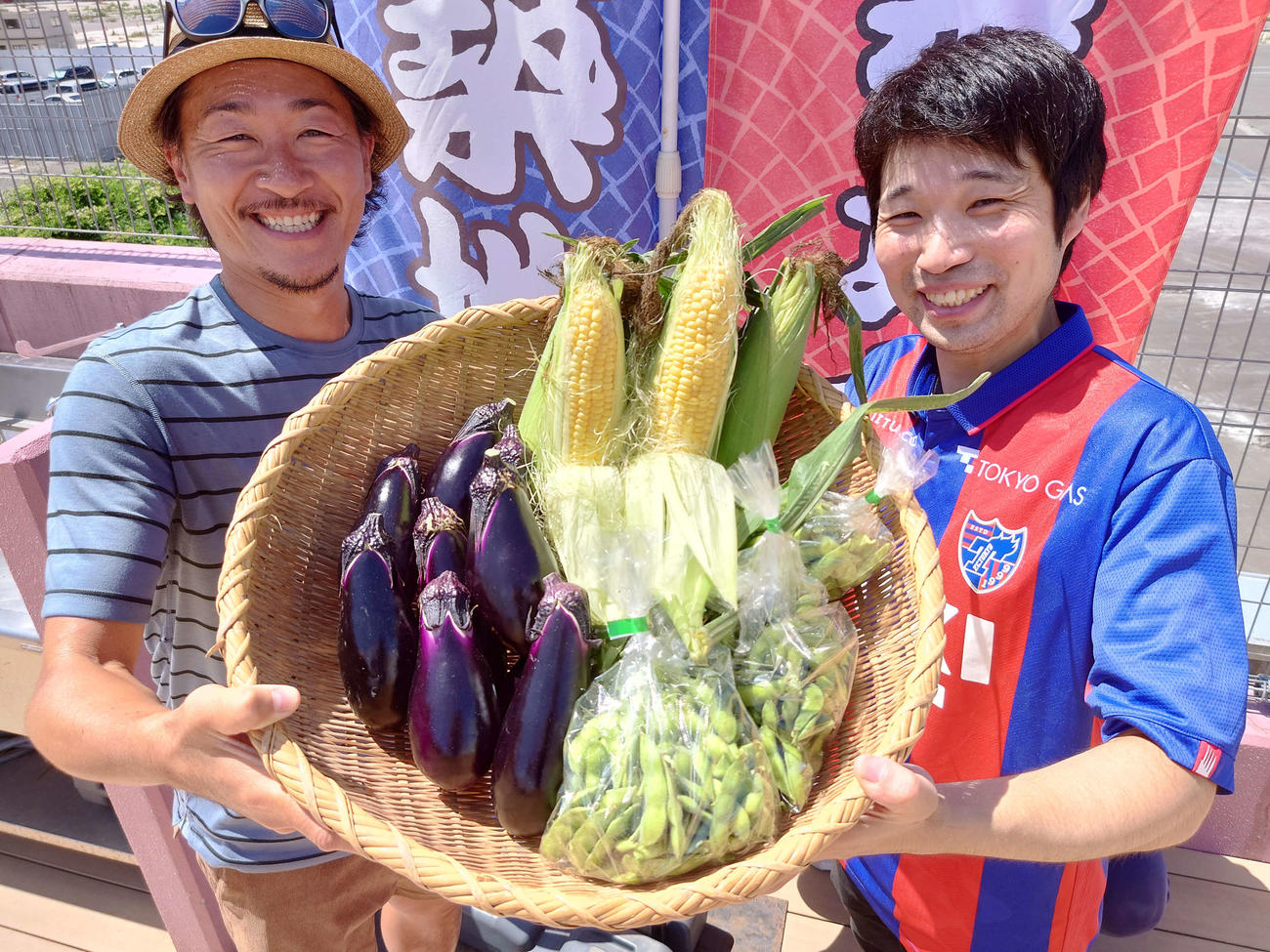 築地魚河岸のバーベキュー場で石川直宏さん（左）は自作トウモロコシと農場仲間の三鷹市の伊藤園でつくられたナスとエダマメも振る舞った。右は協力者の築地場外「藤本商店」の藤本貴也さん（撮影・寺沢卓）