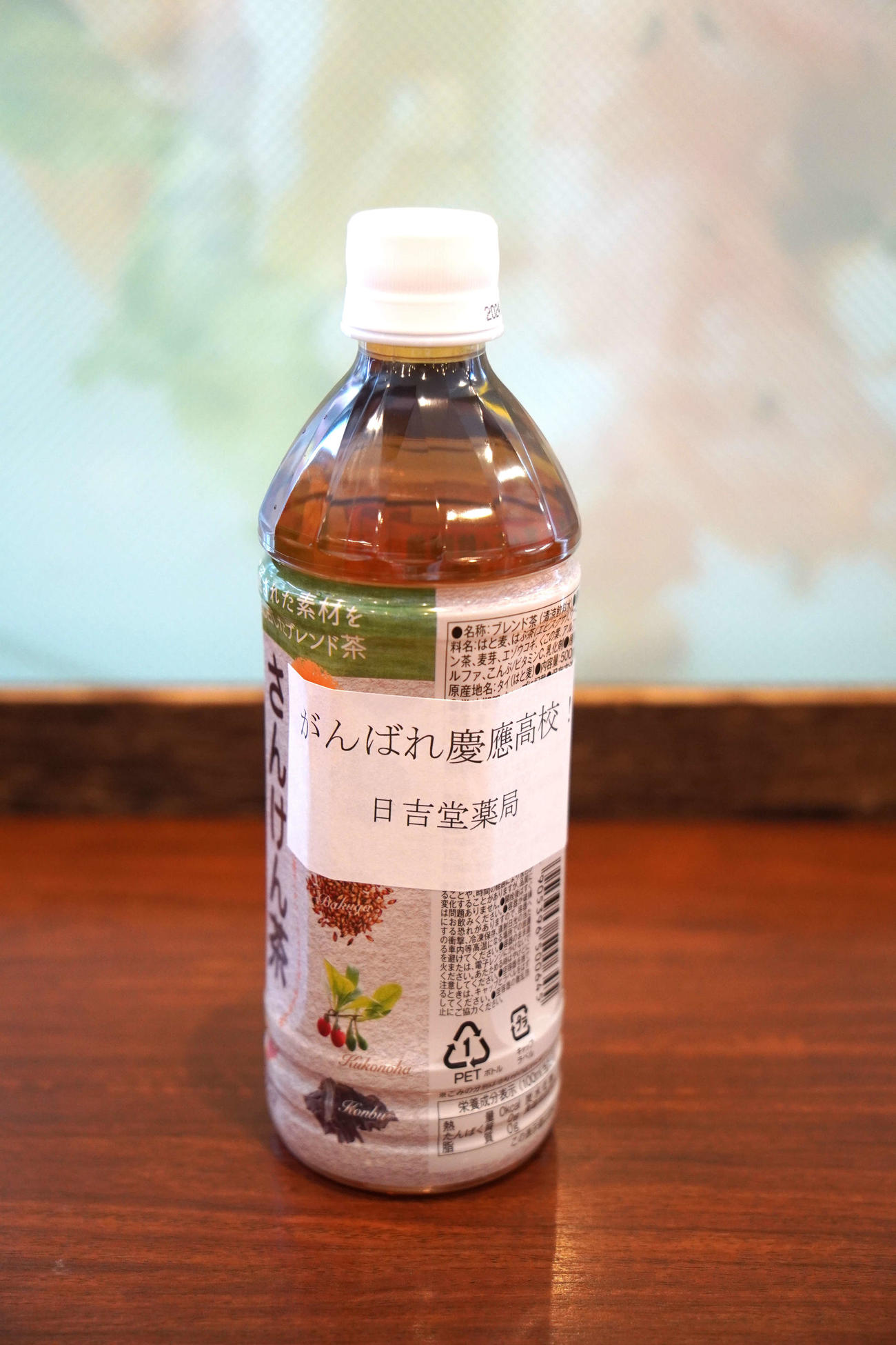 日吉堂薬局が来客に配布する「がんばれ慶応高校！」と書かれたラベルを貼ったお茶（撮影・沢田直人）