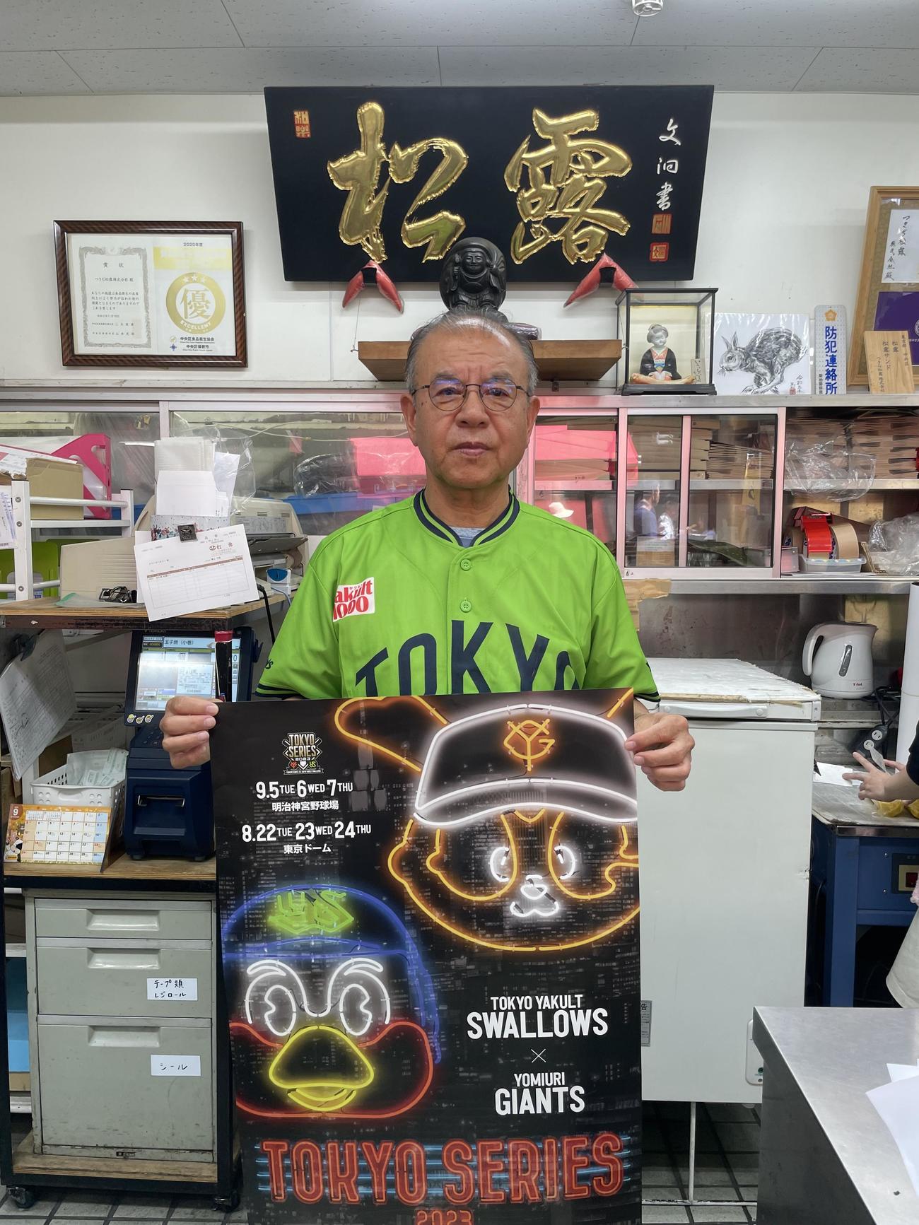 ユニホーム姿でポスターを持つ松露の斎藤元志郎会長
