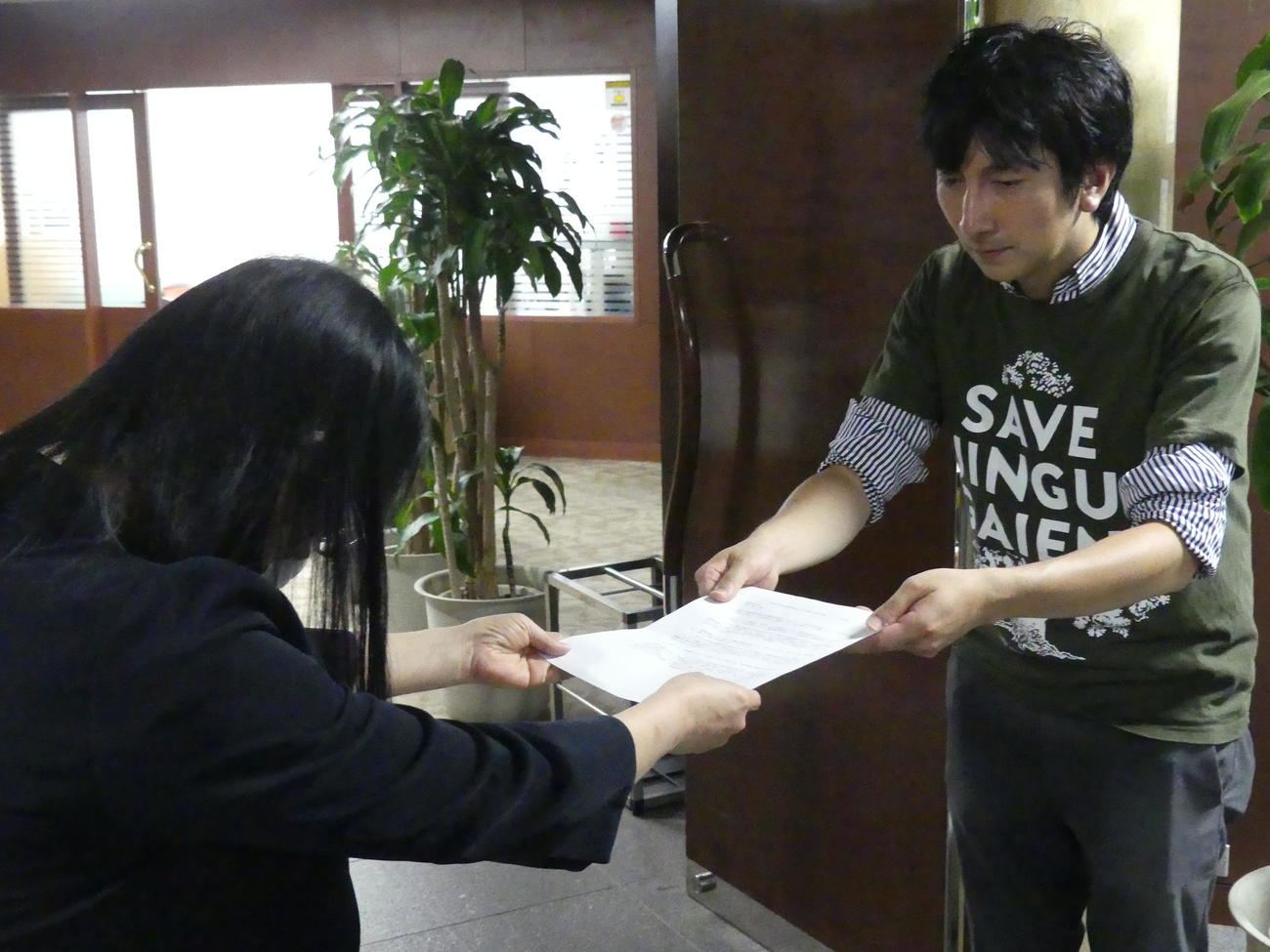 事業者側から新宿区に出された樹木伐採申請を許可しないよう求めた要望書を、区側に提出する大沢暁さん（右）（撮影・中山知子）