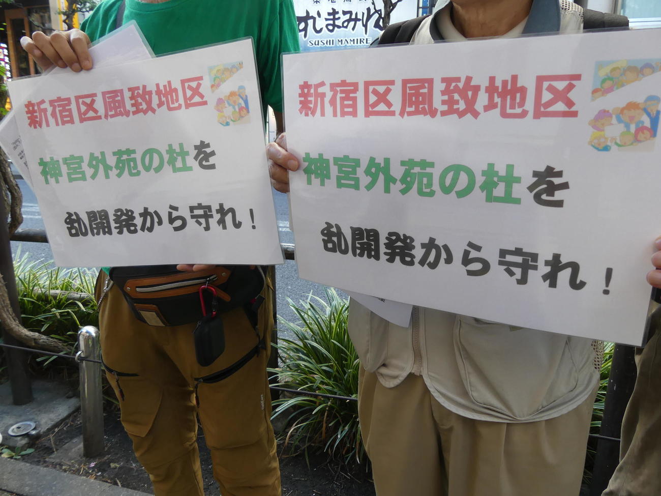 事業者側から新宿区に出された樹木伐採申請を許可しないよう求め、新宿区役所前で市民らが抗議のボードを掲げた（撮影・中山知子）