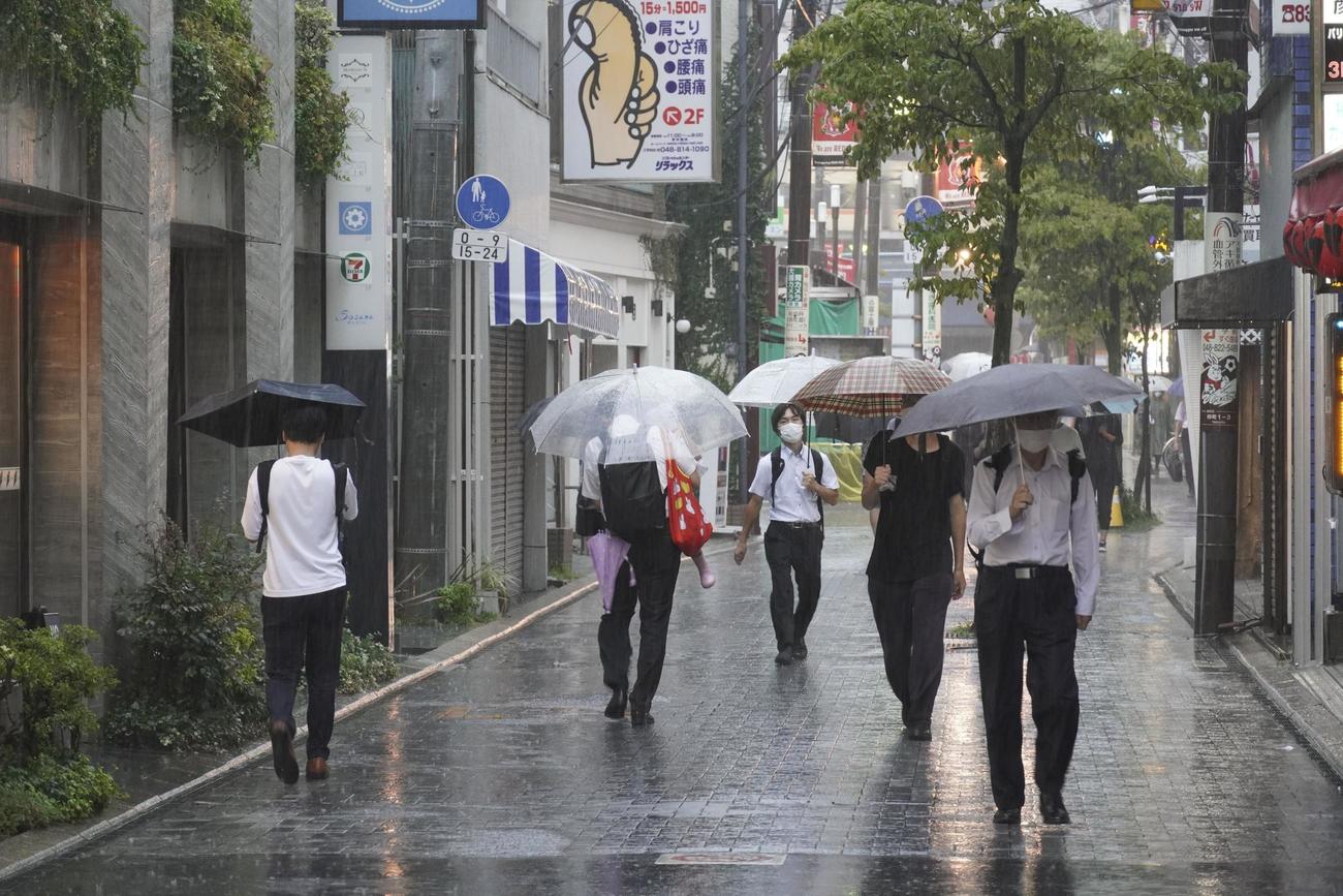 雨の中、通勤する人ら（共同）