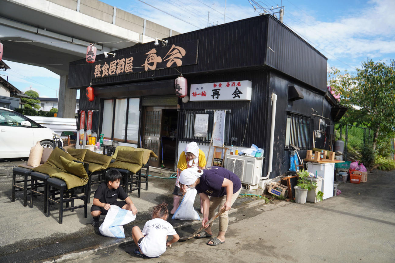 店前の泥や砂を掃除する飲食店「再会」の樋口礼子さん（右から2人目）ら（撮影・沢田直人）