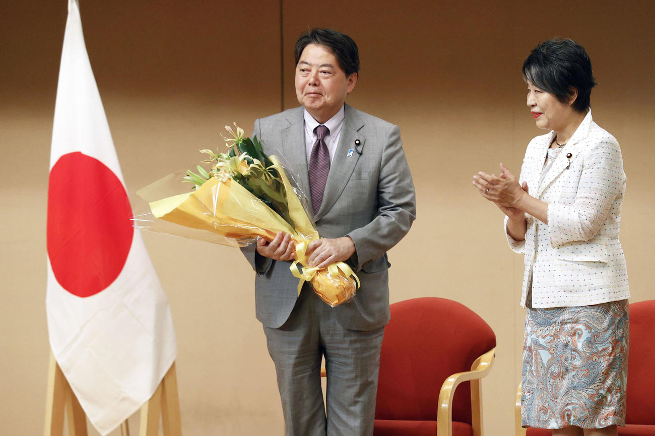 交代式で職員から花束を受け取った林前外相。右は上川外相（共同）