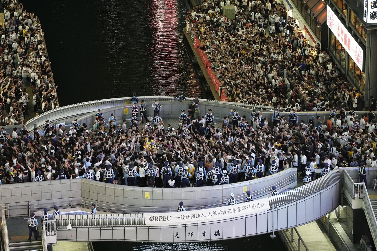大阪・道頓堀に集まった人たち。戎橋の欄干には警察官が並んでいた（共同）