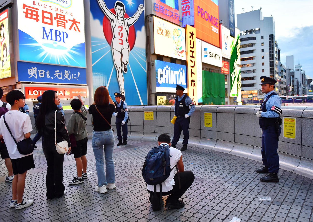 道頓堀の戎橋では警察官が立ち止まらないよう歩行者に注意を促す（撮影・清水貴仁）