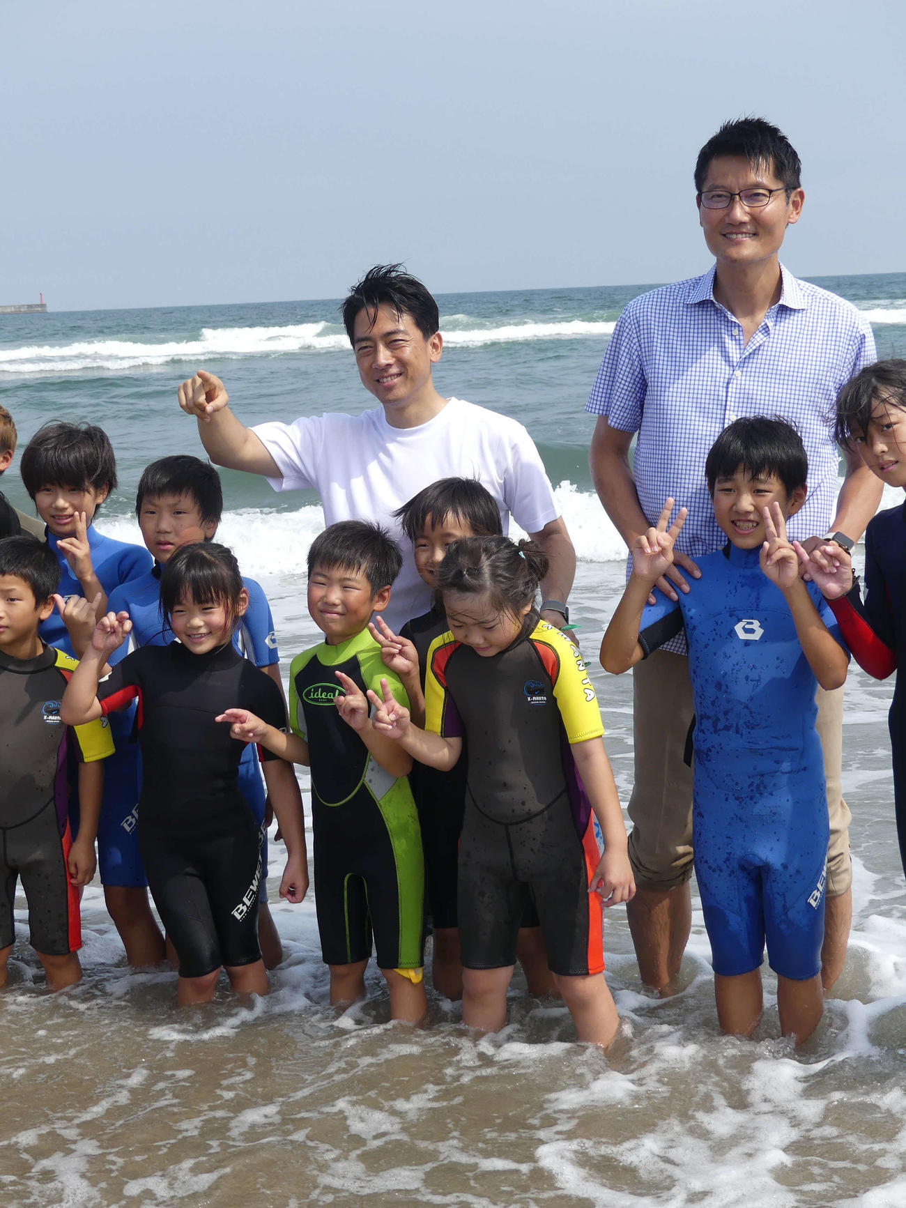 サーフィンを楽しむ子どもたちとふれあう小泉進次郎元環境相（後列中央）。右は朝日健太郎環境政務官（撮影・中山知子）