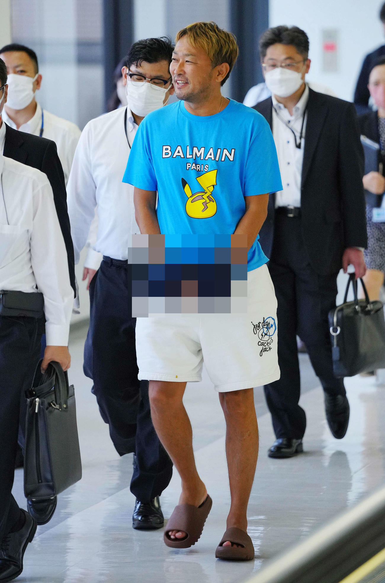 2023年6月4日　帰国し逮捕されたガーシーこと東谷義和容疑者（中央）は捜査員と談笑しながら移動する※写真は一部加工