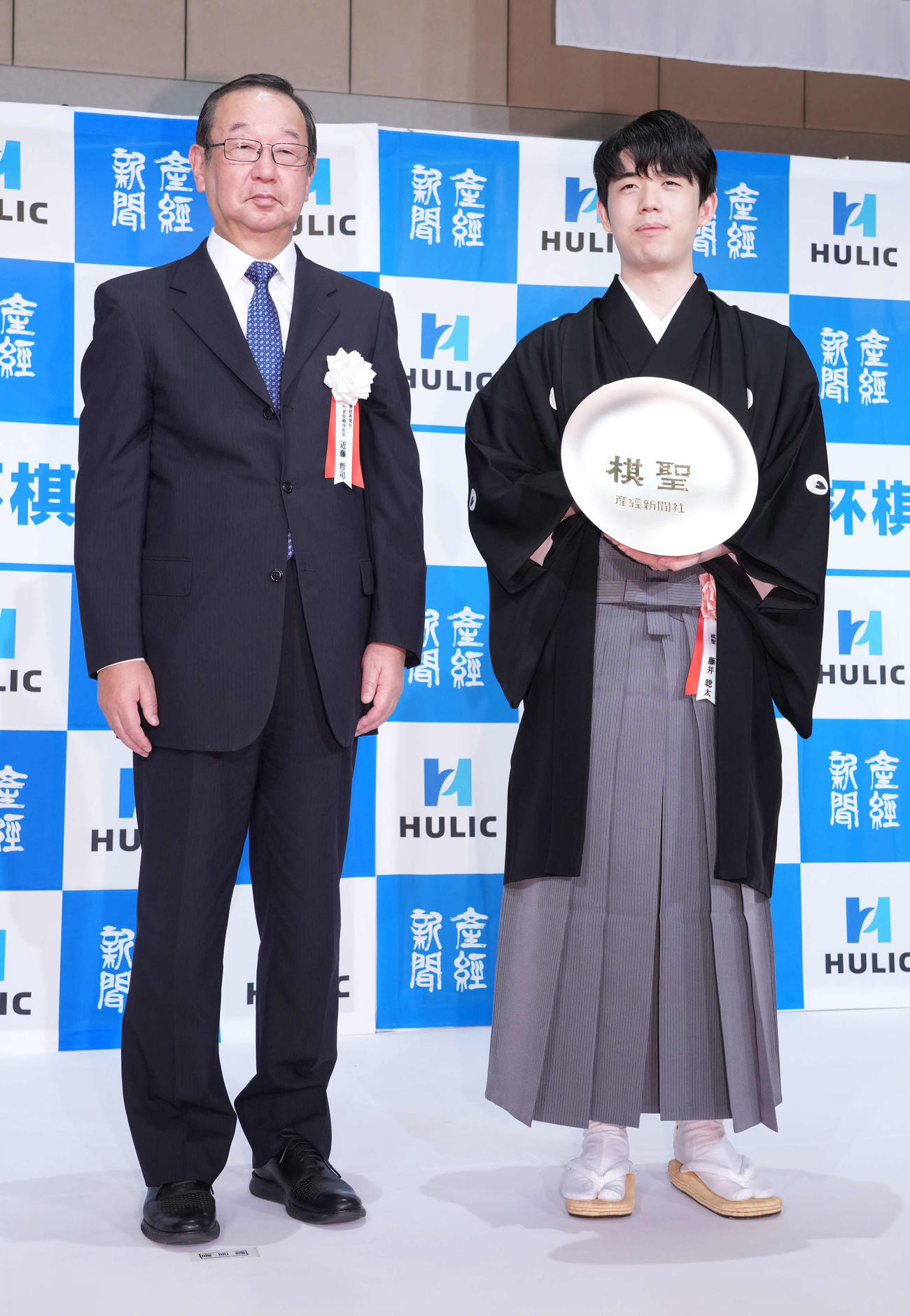 第94期ヒューリック杯棋聖就位式で産経新聞社の近藤代表取締役社長（左）から贈呈された賞杯を披露する藤井棋聖（撮影・小沢裕）