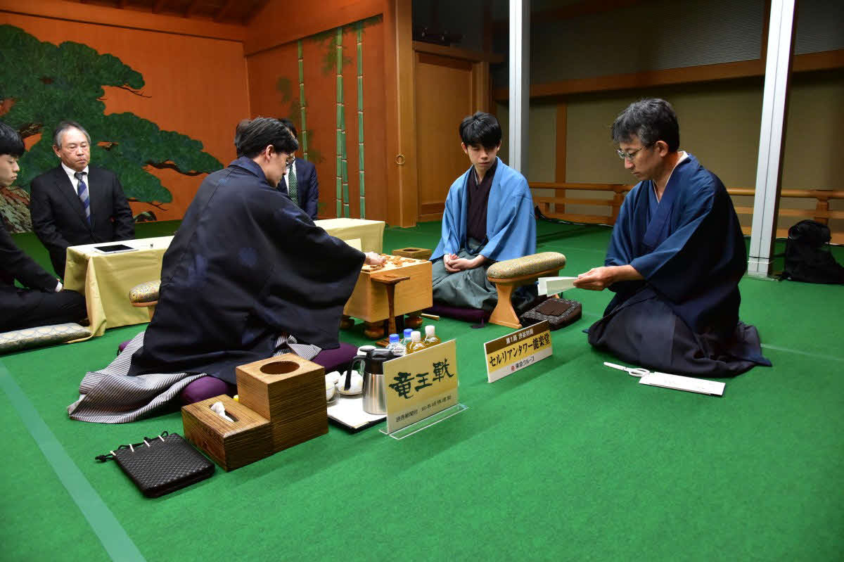 竜王戦第1局2日目は伊藤匠七段（左）の封じ手を立会人の佐藤康光九段（右）が開封して再開（中央は藤井聡太竜王、日本将棋連盟提供）