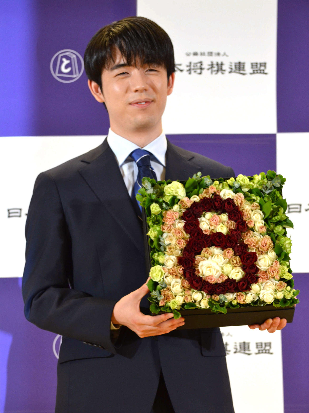将棋の駒と8冠の数字「8」を表現したフラワーボックスを手に笑みを浮かべる藤井聡太8冠（撮影・赤塚辰浩）