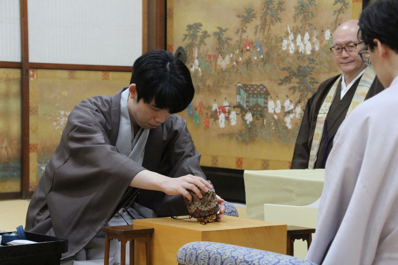 駒袋から駒を盤上に出す藤井聡太8冠（日本将棋連盟提供）
