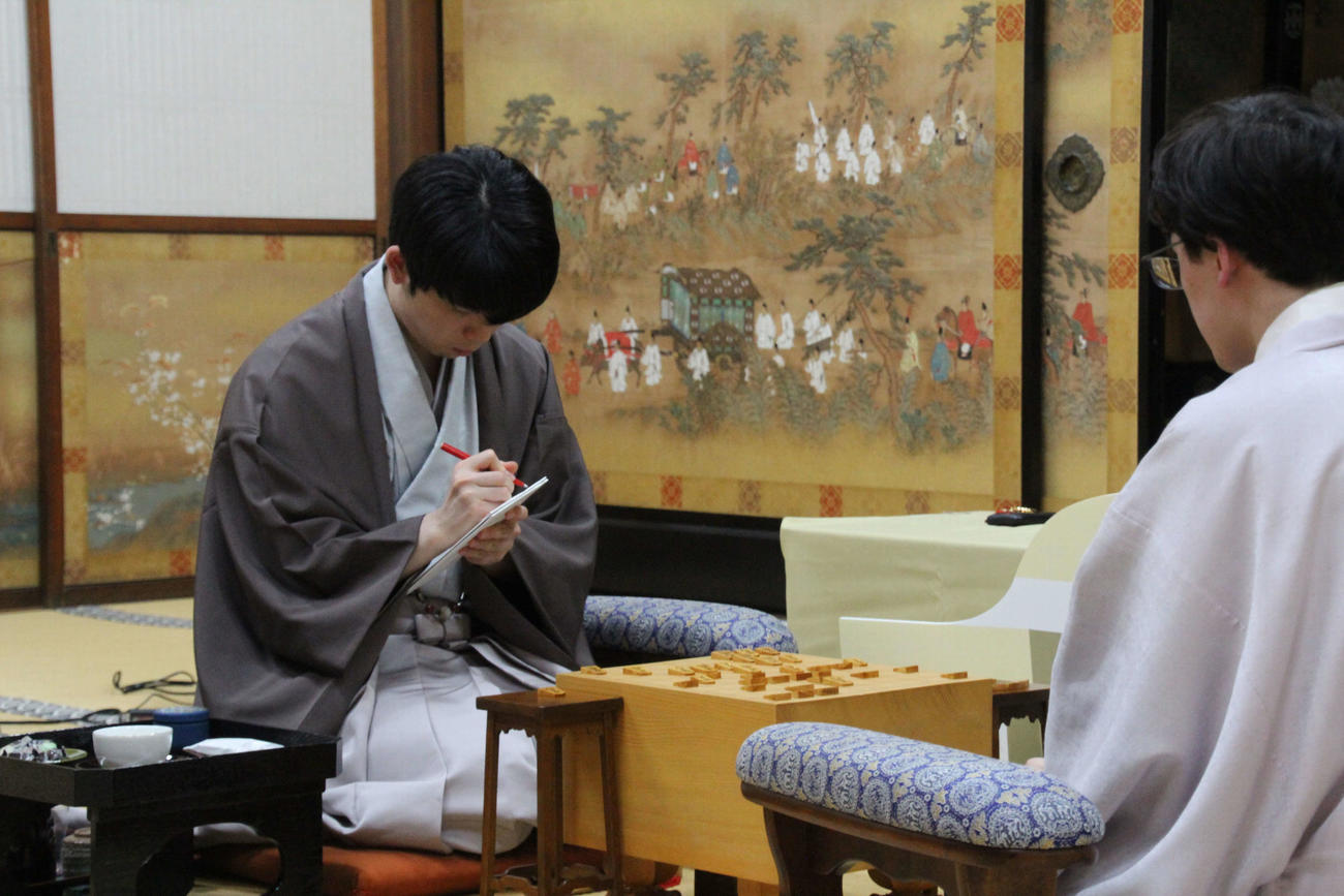 伊藤匠七段の封じ手の封筒にサインする藤井聡太8冠（日本将棋連盟提供）