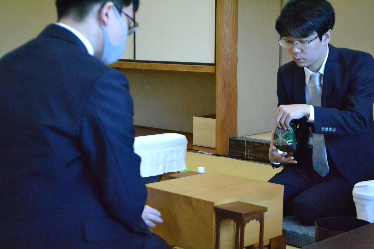 上座の棋士の務めとして駒袋から駒を取り出す豊島将之九段（右、左は永瀬拓矢九段）