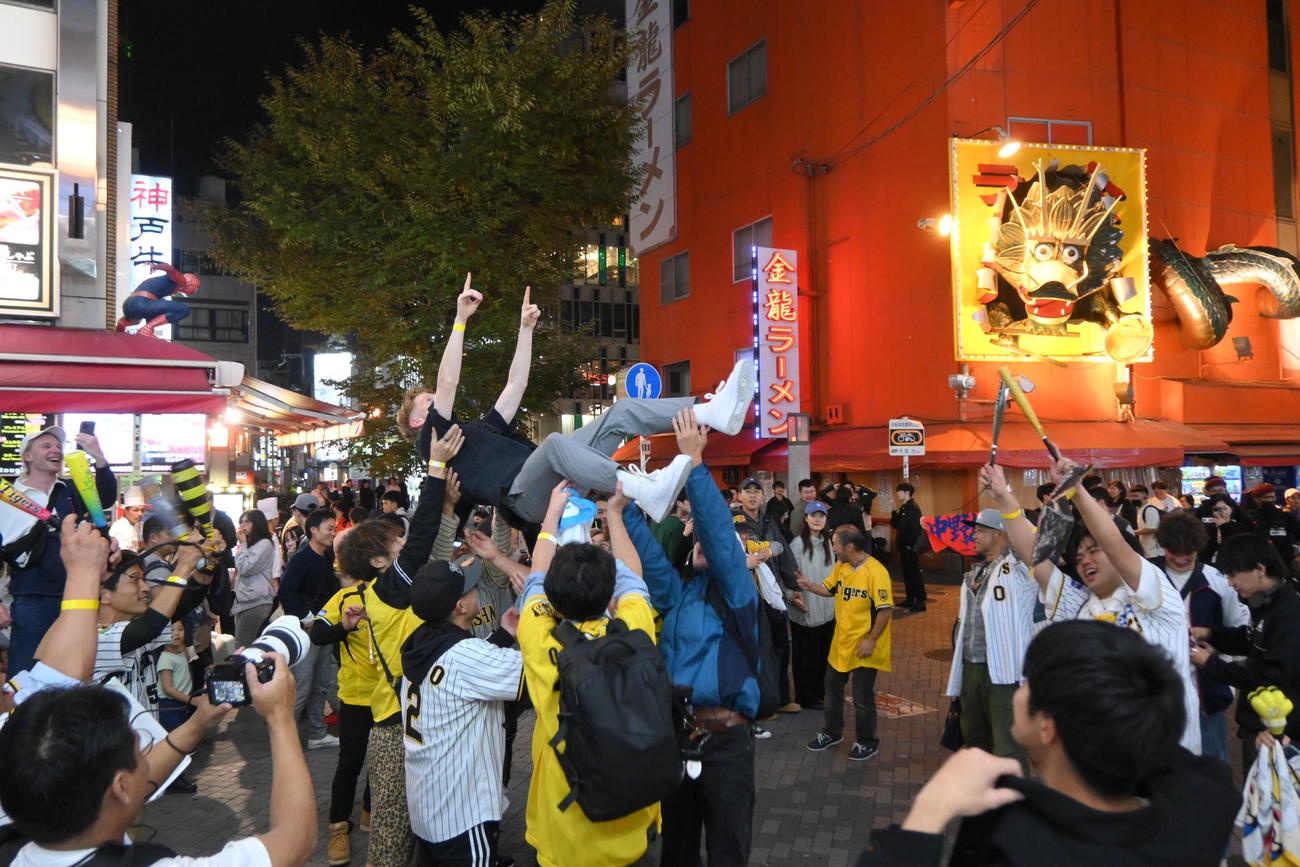 大阪・ミナミの戎橋近くの路上では阪神タイガースの38年ぶりの日本一王手にファンが喜びのあまり外国人観光客も胴上げした（撮影・松浦隆司）