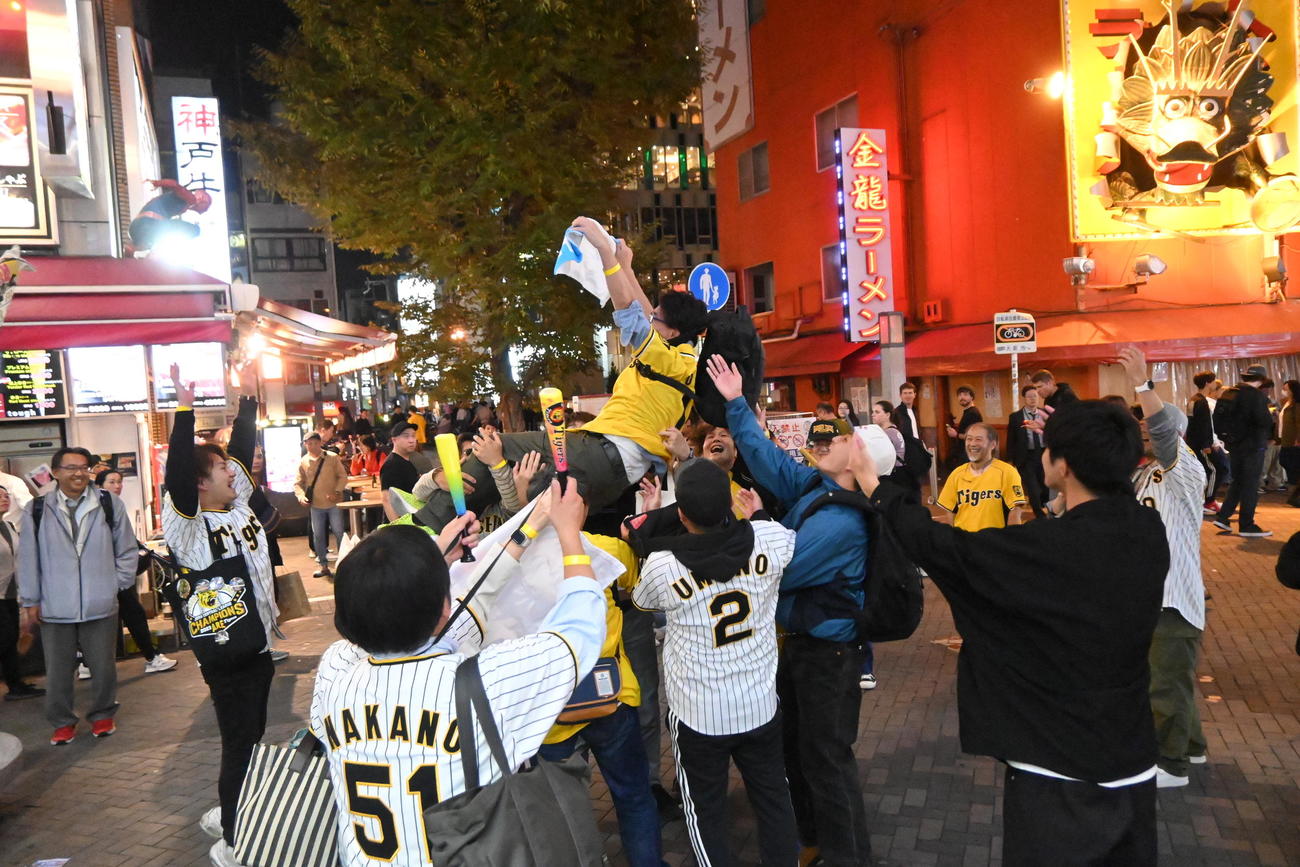 大阪・ミナミの戎橋近くの路上では阪神タイガースの38年ぶりの日本一王手にファンが“王手胴上げ”で歓喜を声を上げた（撮影・松浦隆司）