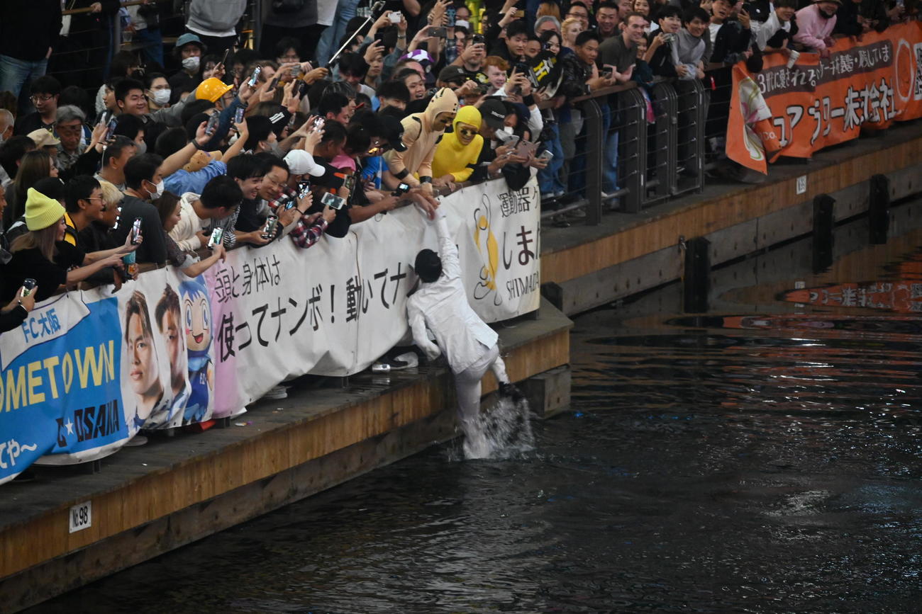 大阪・ミナミの戎橋の遊歩道からダイブし、“行方不明”になる前に自力で上がり、仲間に助けられた「カーネル・サンダース人形」のコスプレをした男性（撮影・松浦隆司）