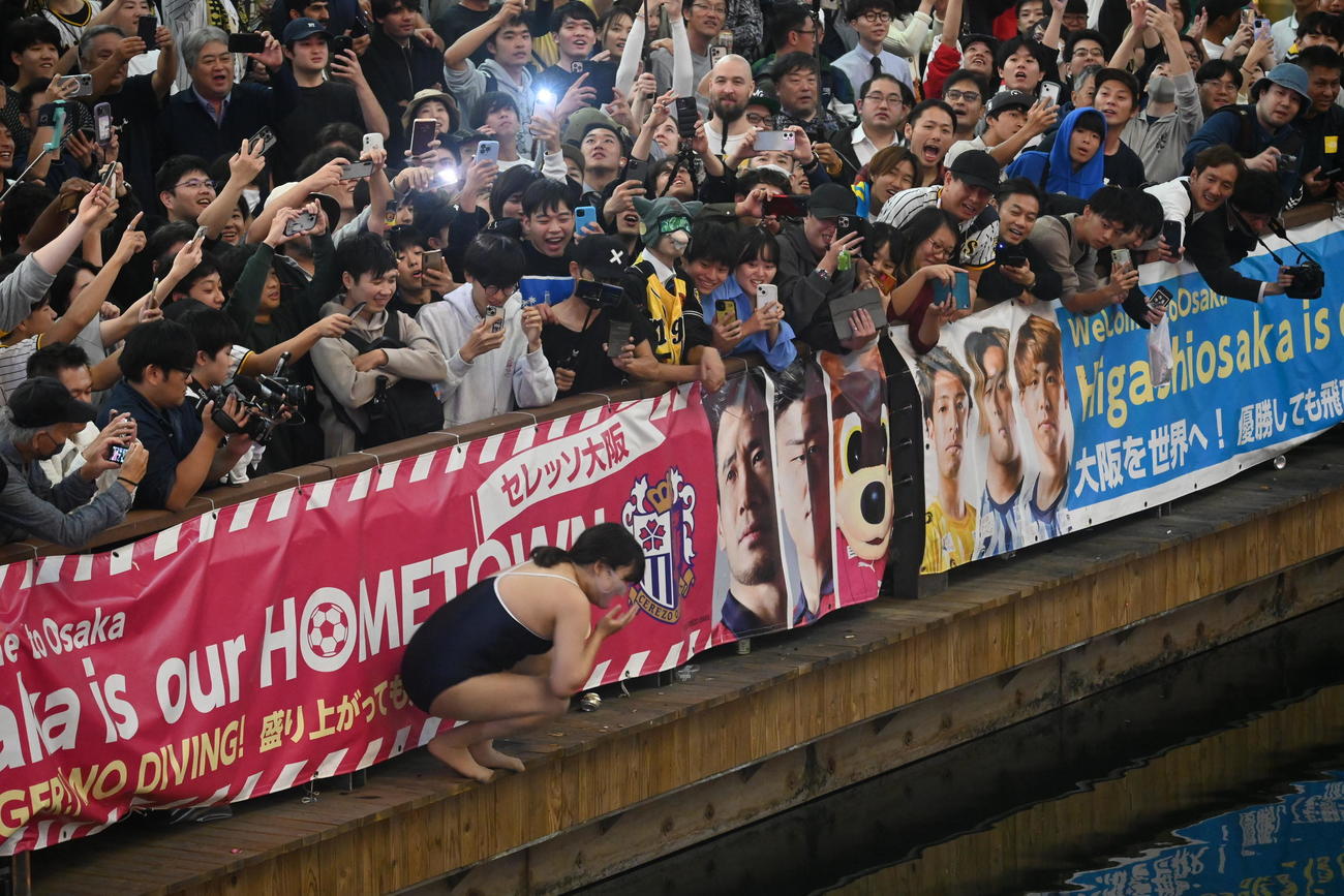大阪・ミナミの戎橋の遊歩道から「プチ・ダイブ」を決めた水着の女性（2023年11月5日撮影）