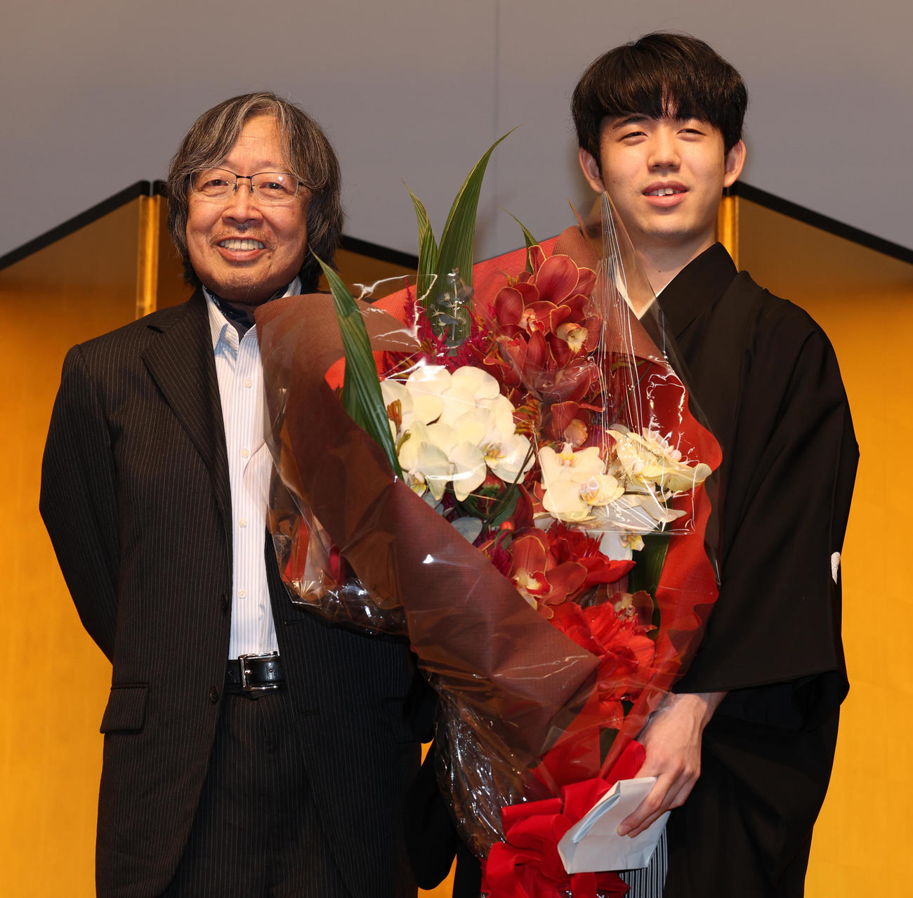 大崎善生氏（左）から花束を受けとる藤井王位（撮影・野上伸悟）