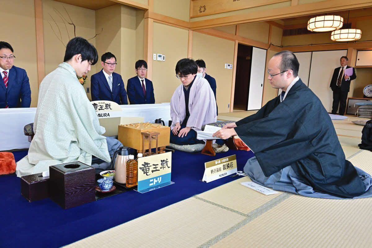 藤井聡太竜王（左）が伊藤匠七段（中央）に3連勝して迎えた竜王戦第4局は立会人の渡辺明九段（右）が封じ手を開封して対局再開（日本将棋連盟提供）
