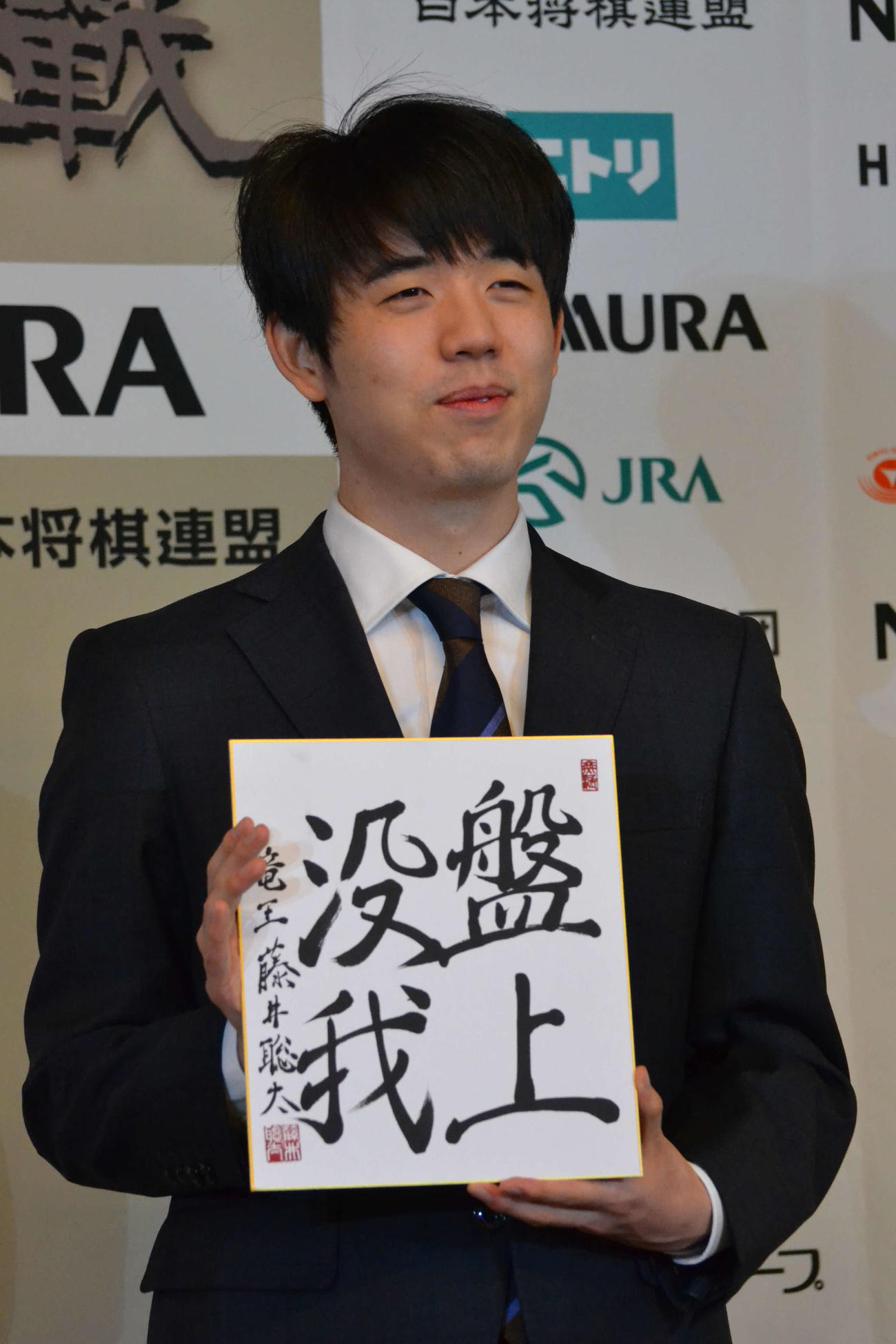 一夜明け会見で「盤上没我」と揮毫（きごう）した色紙を手にする藤井聡太竜王