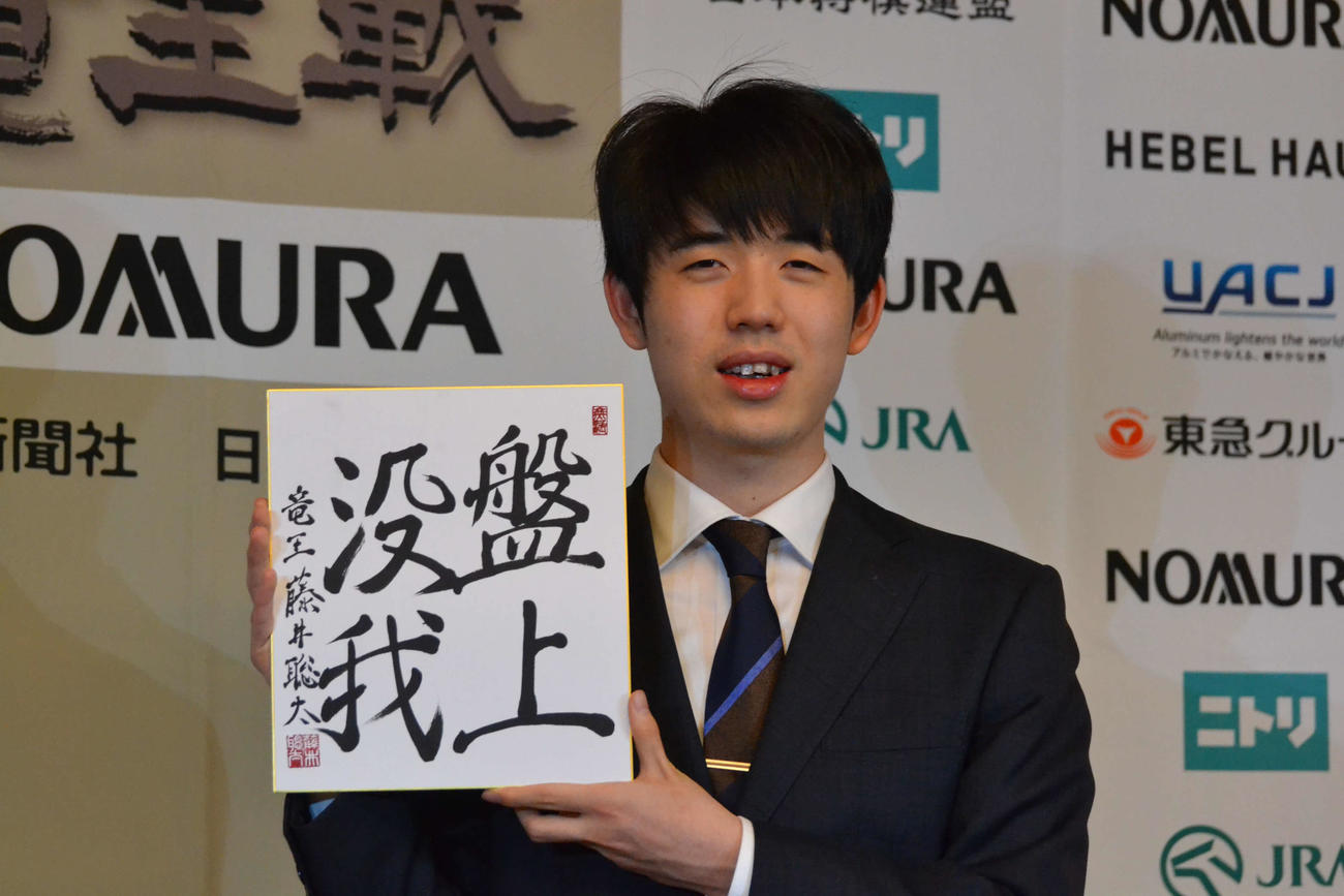 一夜明け会見で「盤上没我」と揮毫（きごう）した色紙を手にする藤井聡太竜王