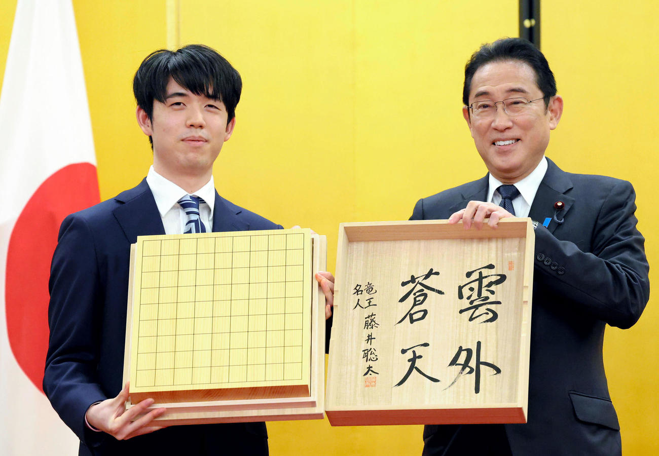 内閣総理大臣顕彰の返礼として、将棋盤を岸田首相に手渡した将棋の藤井聡太八冠（左）（代表撮影）