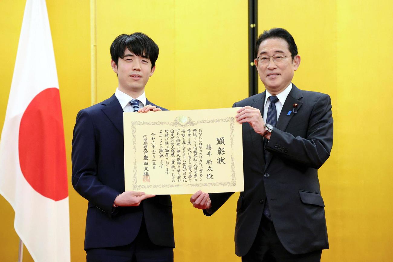岸田首相から内閣総理大臣顕彰の顕彰状を贈られる将棋の藤井聡太八冠（左）（代表撮影）