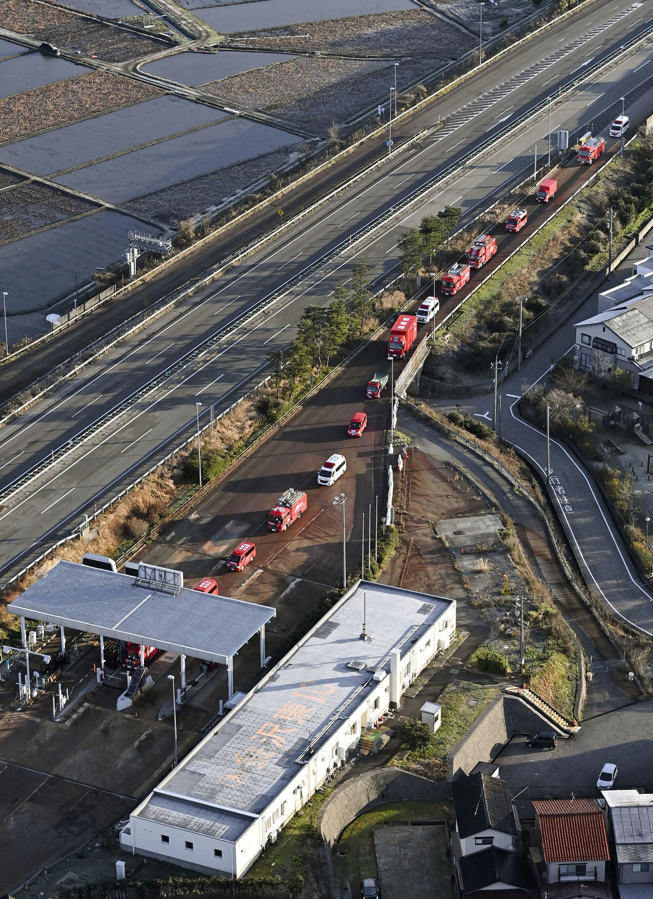 北陸自動車道の出口に並ぶ消防車と救急車＝2日午前8時7分、石川県の金沢東インター（共同通信社ヘリから）