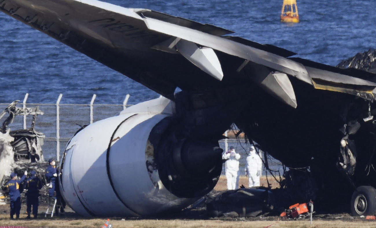 羽田空港の滑走路で炎上し焼け焦げた日航機を調べる警視庁の関係者ら（共同）