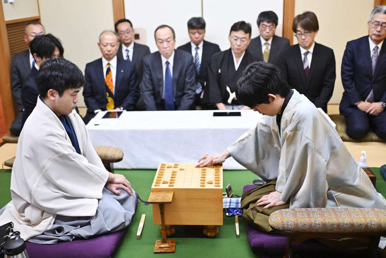 第73期王将戦七番勝負の第1局、2手目を指す藤井王将（右）。左は挑戦者の菅井八段（同左）（代表撮影）