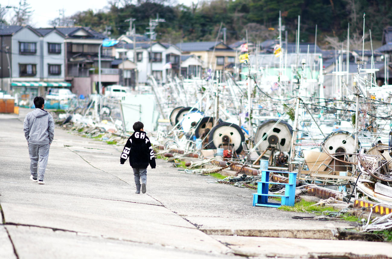 輪島港にはたくさんの漁船が並べられていた。能登半島地震での海底隆起による水位低下、港の電気が止まっていることにより冷蔵庫が使えない、輸送確保ができないなど問題山積みにより再開のめどはたっていないという。漁港を歩いていた漁師の親子は自分の船の船底が座礁していないか確認に来たと話していた。（撮影・横山健太）