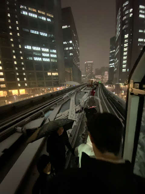 降雪で新橋駅手前の坂を上ることができず、運行がストップした、ゆりかもめを降り、軌道上を歩いて汐留駅に避難する乗客（撮影・村上幸将）