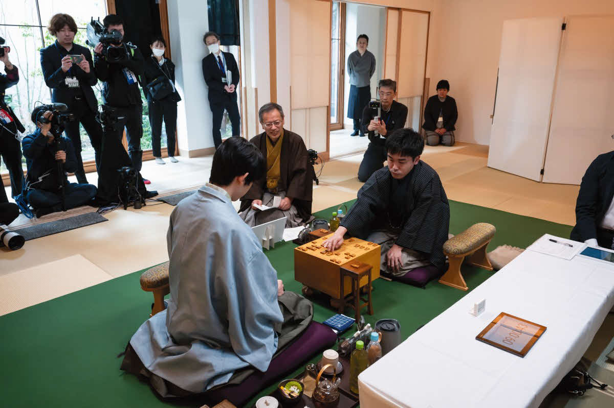 初日に封じ手を行った菅井竜也八段（右）の指し手を立会人の中村修九段（中央）が開封して対局再開（左は藤井聡太王将、日本将棋連盟提供）